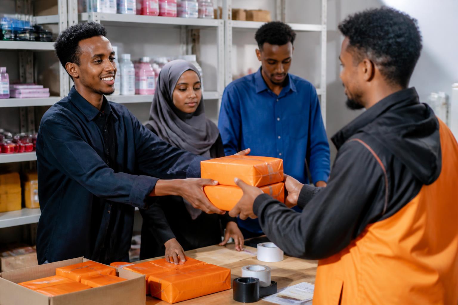 Trainees handing packaged orders to a dispatch courier